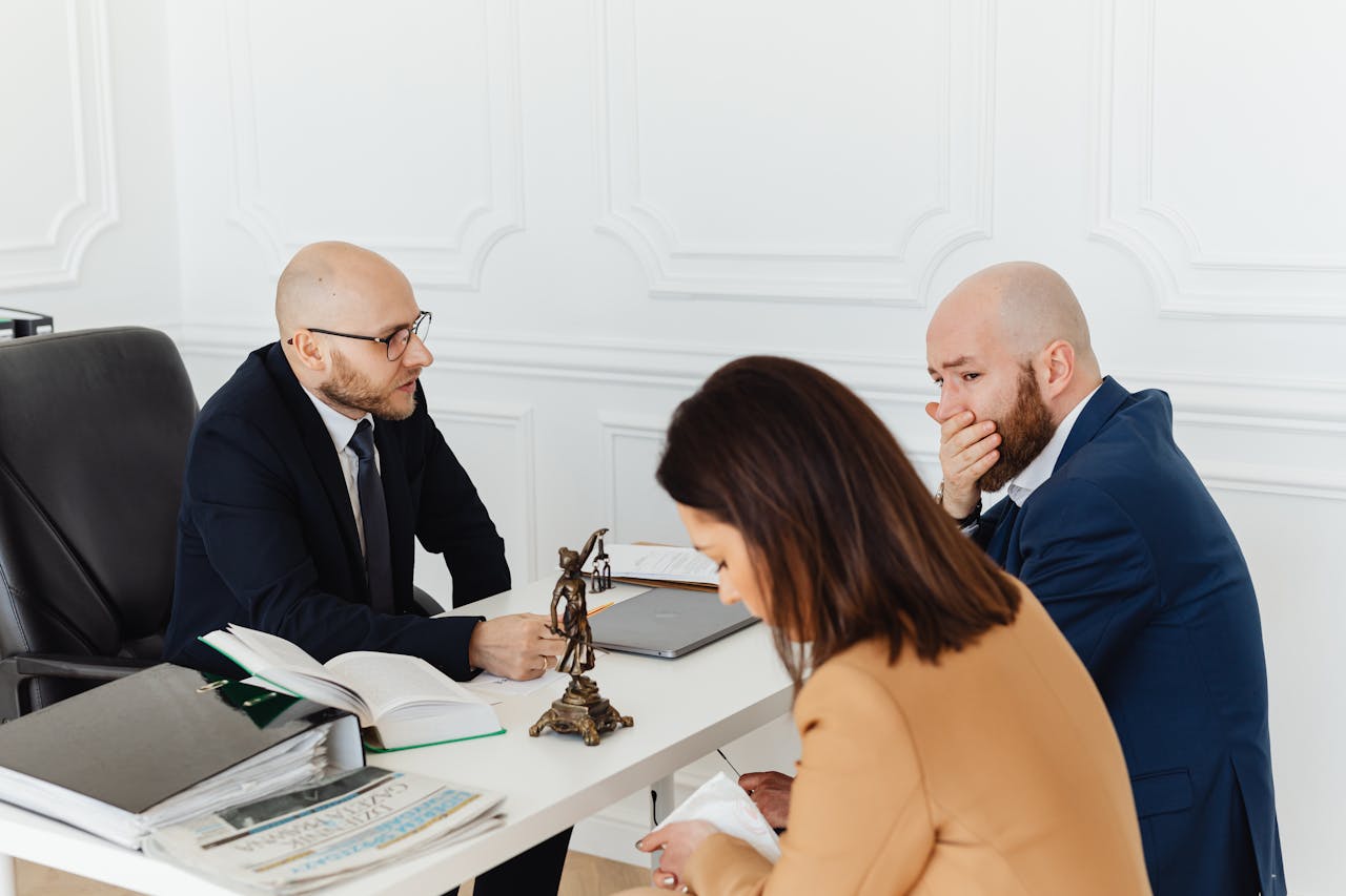 how-it-works A serious legal consultation in a professional office environment involving three adults.
